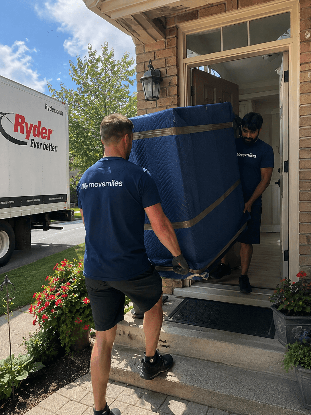Movemiles crew arriving with the truck and carrying a wrapped load to the door