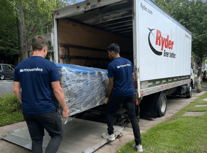 Movemiles movers loading a wrapped item up the ramp into the truck